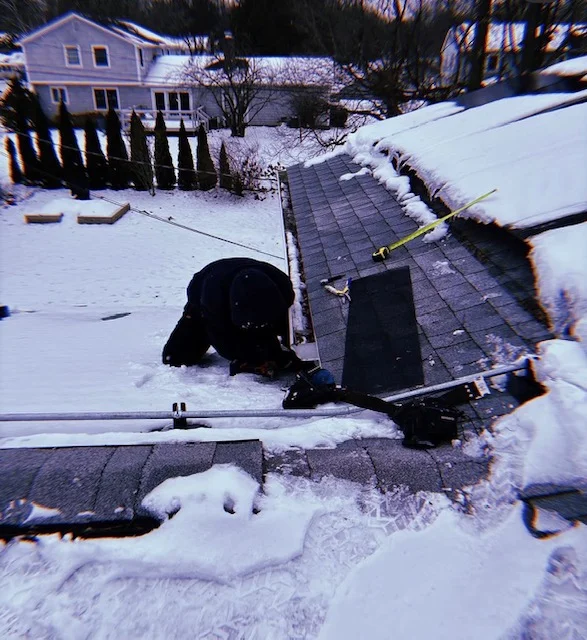Technician inspecting damaged asphalt roof shingles and entry points in winter conditions